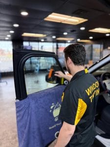 Window tint being installed on a black car in Sacramento